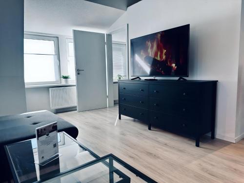 a living room with a black dresser with a tv on it at FeWo Lindenallee II Modernes DG-Apartment in Nordhorn