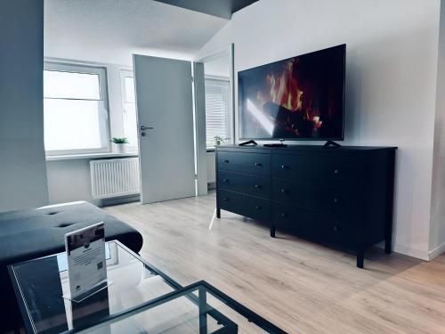 una sala de estar con una cómoda negra con TV. en FeWo Lindenallee II, en Nordhorn