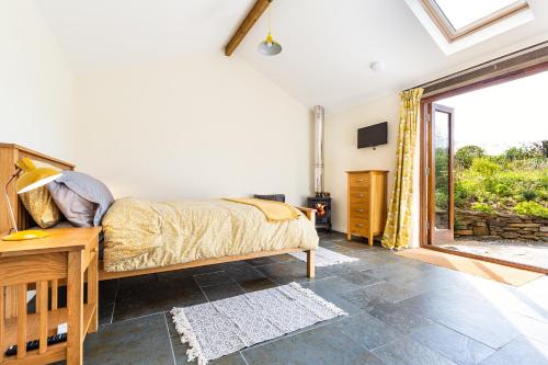 a bedroom with a bed and a large window at The Old Piggery. Cornwall in Liskeard