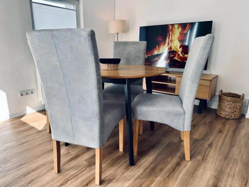 a dining room table with three chairs and a tv at FeWo Euregio II - mit Terrasse in Nordhorn