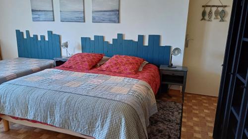 a bedroom with a bed with red pillows on it at Le relais du phare in Gatteville-le-Phare