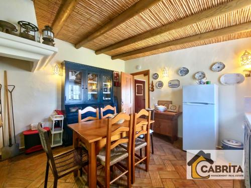 una cucina e una sala da pranzo con tavolo e frigorifero di Quinta dos Medronheiros ad Altura
