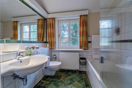 een badkamer met een wastafel, een toilet en een bad bij Seehotel Zarrentin in Zarrentin