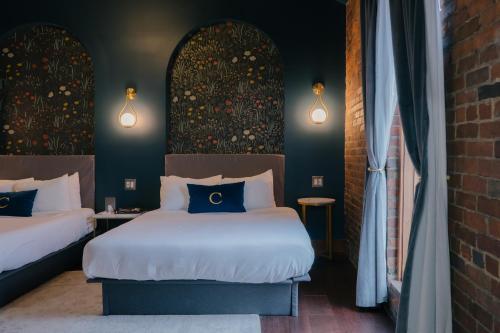 a bedroom with two beds and a brick wall at The Chandler Hotel in Madison