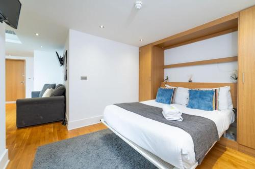 a bedroom with a large white bed with blue pillows at Piccadilly Circus-West End Central London Studio Apartment in London