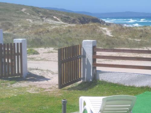 een houten hek met een bank naast het strand bij Coruña Backpackers Hostel in Carballo