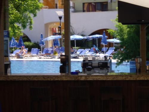 a swimming pool with blue umbrellas and chairs at Relaks w Marina Cape 88 in Aheloy