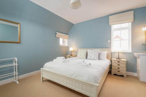 a bedroom with a large white bed with blue walls at Stables Loft - Elie in Elie