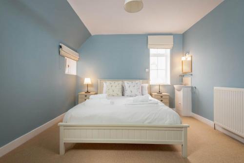 a bedroom with a large white bed with blue walls at Stables Loft - Elie in Elie