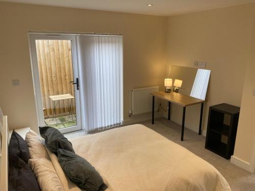 a bedroom with a bed and a desk and a window at Bath road villa in Keynsham