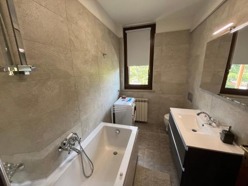 een badkamer met een bad en een wastafel bij DISCOVERY FLAT with pool & bikes in Sirmione