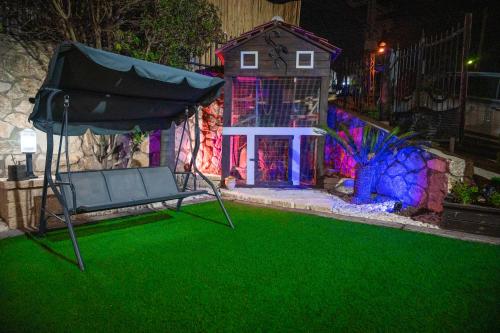 a yard with a green lawn with a chair and a house at bali carmel zimmer & spa in Dāliyat el Karmil