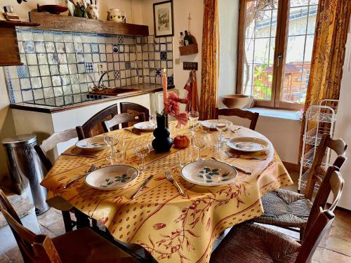 a dining room table with plates and glasses on it at Maison Du Lavoir, Venosc - Les 2 Alpes in Vénosc