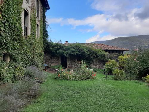 un edificio ricoperto di edera con un cortile fiorito di The Manor House a Barreda