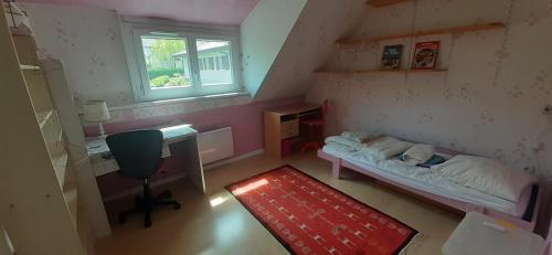 um pequeno quarto com uma cama, uma secretária e uma janela em Sweet quiet home with garden em Annecy