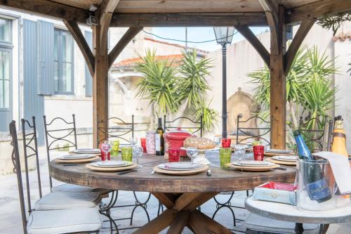 a wooden table with plates and dishes on a patio at La maison de Joséphine - Demeure familiale - 4* in Île dʼAix