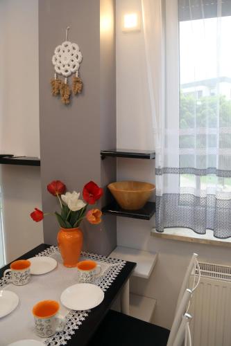 a kitchen with a table with plates and flowers on it at Apartamenty Uniejow "prywatne kapiele termalne" in Uniejow