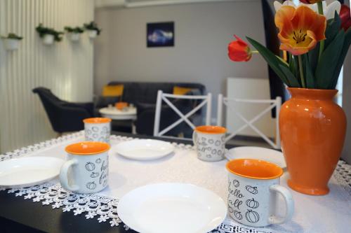 einen Tisch mit Tassen und Tellern und eine Vase mit Blumen in der Unterkunft Apartamenty Uniejow "prywatne kapiele termalne" in Uniejów