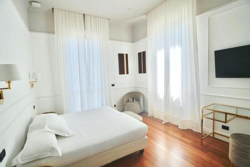 a white bedroom with a bed and a tv at Rechigi Park Hotel in Modena
