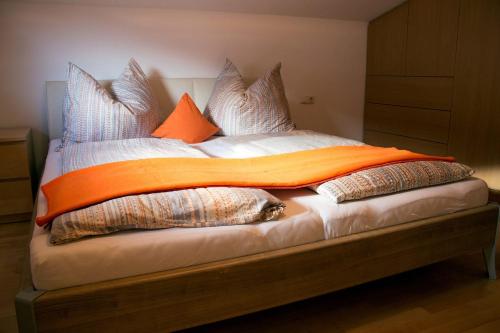 a bed with pillows and an orange blanket on it at Ferienwohnung Kitzbichler im Kaiserwinkl in Kössen