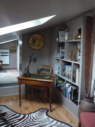 Cette chambre comprend un bureau et une étagère avec des livres. dans l'établissement Les Pensees Chambre Hemingway, à Orléans
