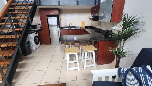 a kitchen with white stools and a counter top at Nautica in Mossel Bay