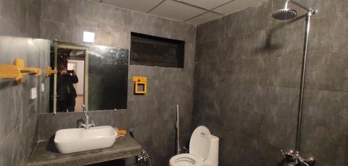 ein Badezimmer mit einem Waschbecken, einem WC und einem Spiegel in der Unterkunft The Teal Cottage in Murree