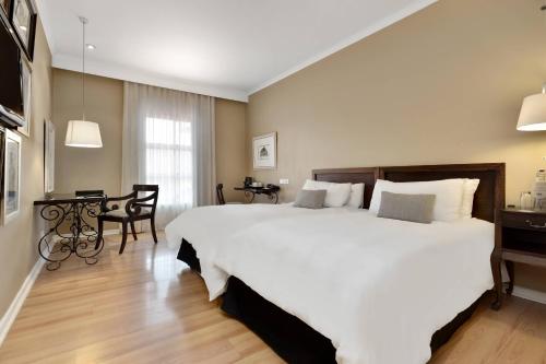 a bedroom with a large white bed and a table at Protea Hotel by Marriott Nelspruit in Nelspruit