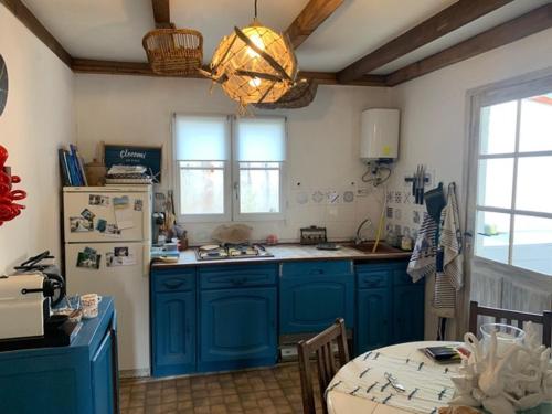 La cuisine est équipée de placards bleus et d'un réfrigérateur blanc. dans l'établissement Villa Clocomi - typique de l'ile d'aix vue mer, à Île-d'Aix