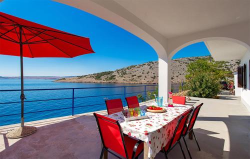 a table with red chairs and a red umbrella on a patio at Amazing Apartment In Jablanac in Jablanac