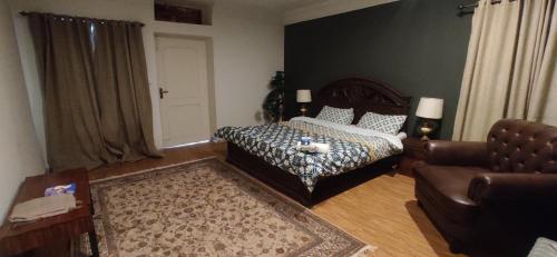 een slaapkamer met een bed, een bank en een stoel bij The Teal Cottage in Murree