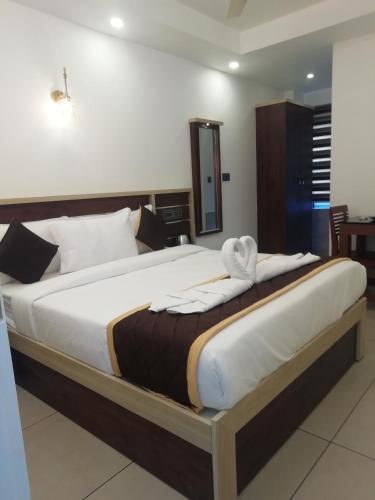 a large bed in a hotel room with at PAUL RESIDENCY in Nedumbassery