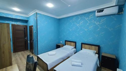 two beds in a room with a blue wall at Volidam Hotel in Karmana