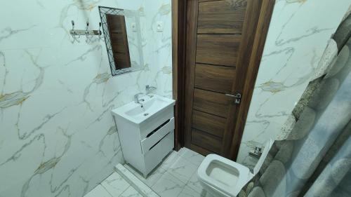 a white bathroom with a sink and a toilet at Volidam Hotel in Karmana