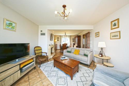 a living room with a couch and a tv at Maison Lutène - Avec jardin terrasse in Sartilly