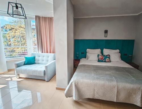 a bedroom with a bed and a couch and a window at Ava Relax Apartments in Świnoujście