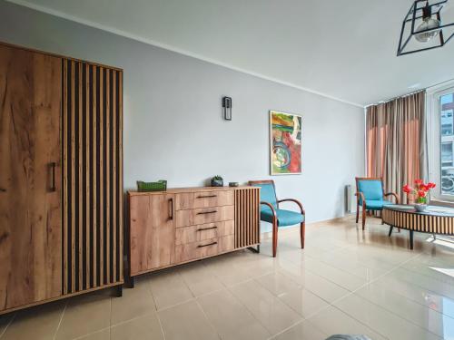 a living room with a wooden cabinet and blue chairs at Ava Relax Apartments in Świnoujście