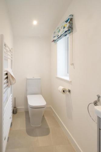 a white bathroom with a toilet and a window at Annie's House in Thorpeness