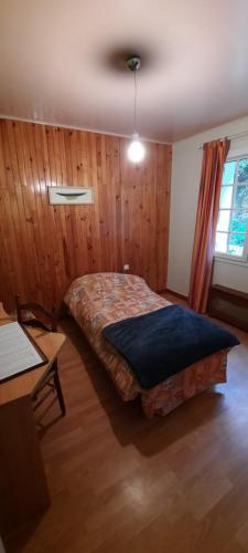 a bedroom with a bed in a room with wooden walls at aux 2 oies in Plouider