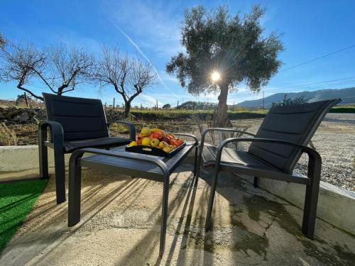 two chairs and a table with a bowl of fruit on it at Samorinha House in Assares