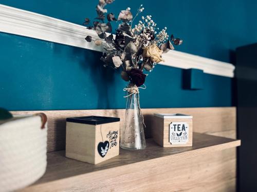 un vase de fleurs sur une table avec deux boîtes dans l'établissement L'Haussmanien au Coeur de ville, à Aurillac
