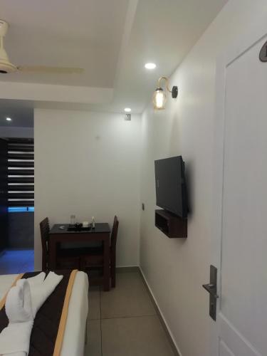 a room with a bed and a table and a tv on the wall at PAUL RESIDENCY in Nedumbassery