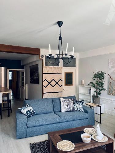 un salon avec un canapé bleu et une table dans l'établissement L'Haussmanien au Coeur de ville, à Aurillac