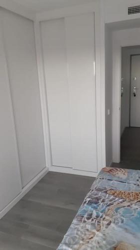 a white room with a bed and a hallway at Camporrosso Pool View Apartment in Finestrat