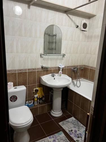 a bathroom with a sink and a toilet and a mirror at City Center Apartment in Tashkent