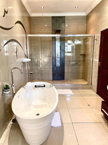 a large bathroom with a tub and a shower at Villa Tasha Luxury Suites, Lanseria in Johannesburg
