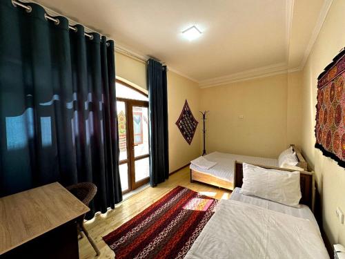 a small room with two beds and a window at Art Suzani National House Hotel in Bukhara