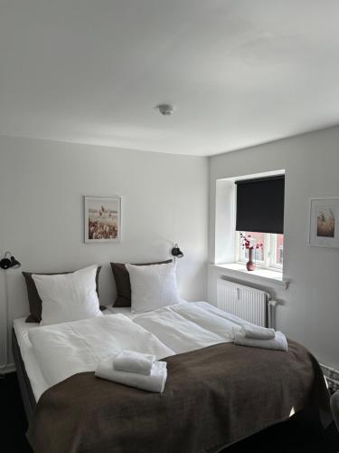 a white bedroom with a large bed with two towels on it at VISIONHOUSE Hotel in Frederikssund