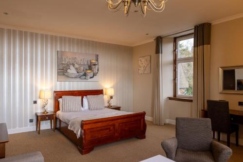 a bedroom with a bed and two chairs and a window at Rosslea Hall Hotel in Rhu