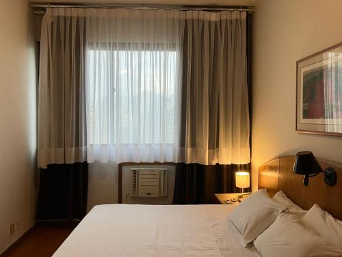 1 dormitorio con cama y ventana grande en Apart Hotel Guignard, en Belo Horizonte